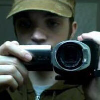 a screenshot of jay filming himself in a bathroom mirror, face partially obscured by the camera he holds